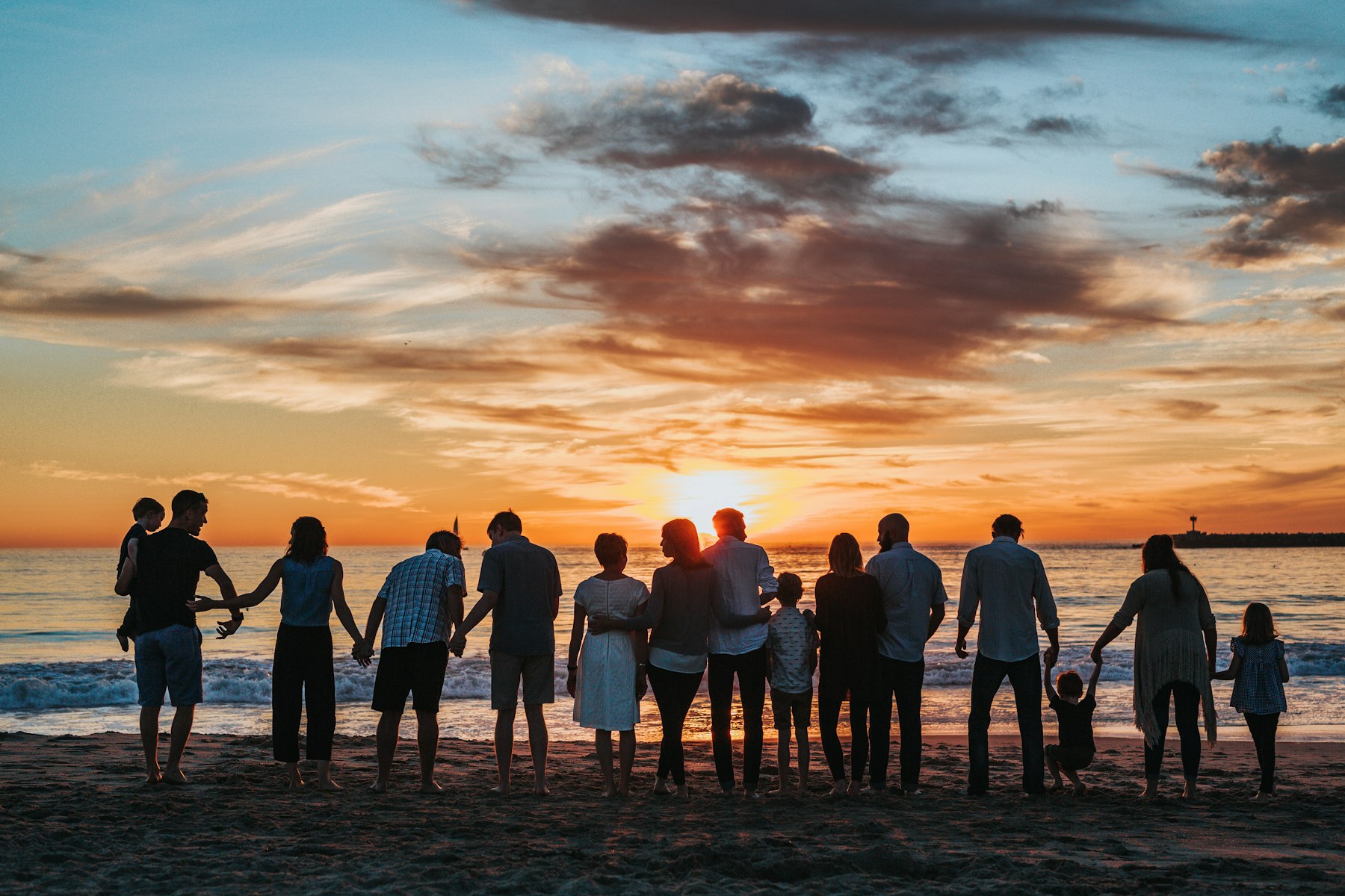 Family standing together on a beach at sunset